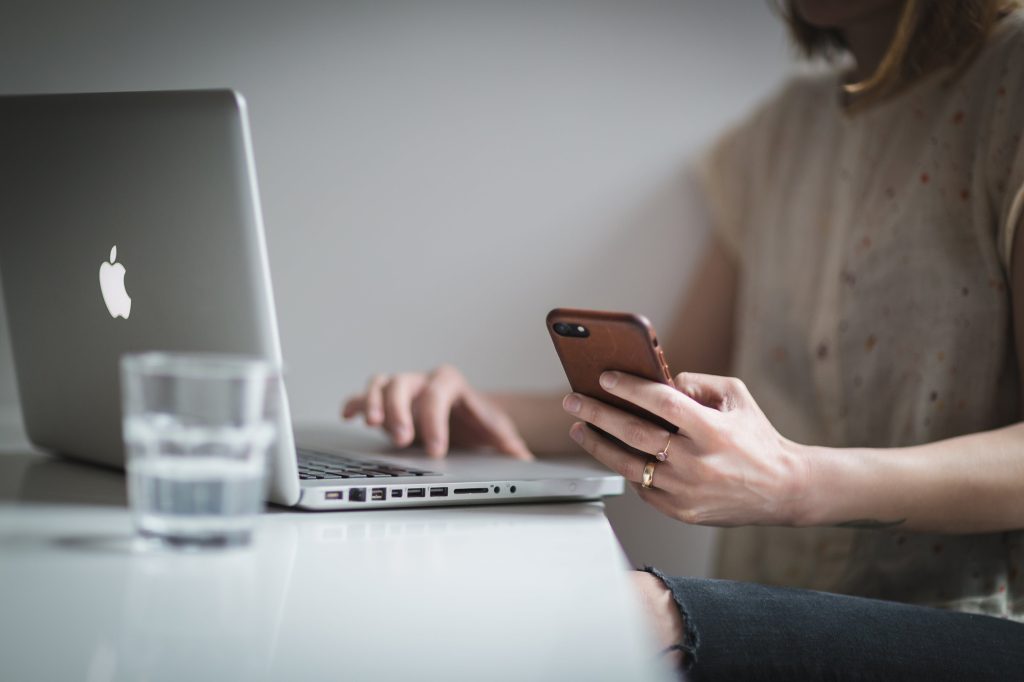 Woman working on phone and laptop