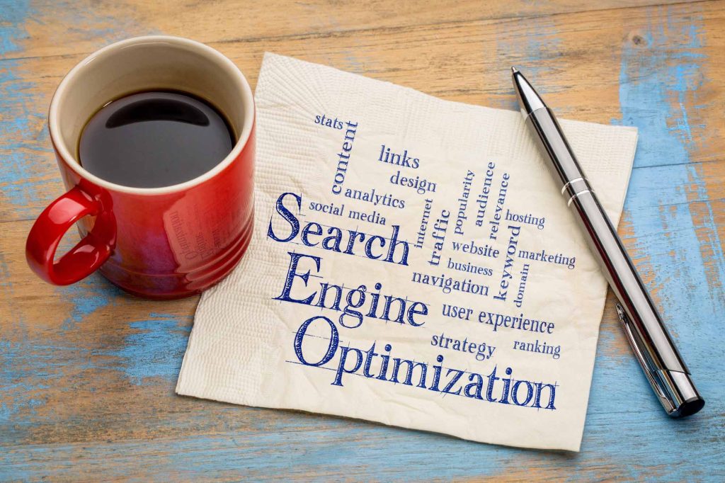 Napkin with words related to search engine optimization written on it surrounded by coffee cup and pen